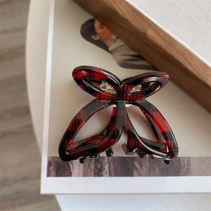 Vintage red plaid butterfly hair claw clip with cutout design on a warm-toned background