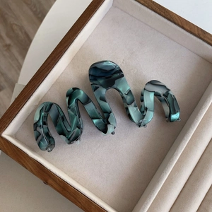 Detailed view of large marble wave hair claw clip inside a luxury wood jewelry box