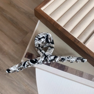 Detail of large acetate hair claw clip featuring elegant black and white marble texture