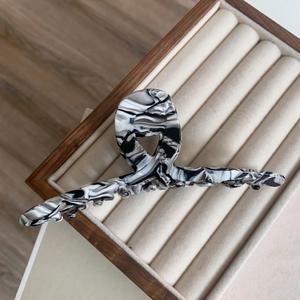Close-up of black and white marbled acetate hair claw clip with large crisscross teeth