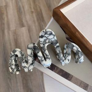 Detail showing wavy acetate shark clip with black and white abstract marble pattern
