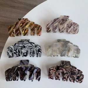 Vue de dessus de six grandes pinces à cheveux en acétate aux textures marbrées