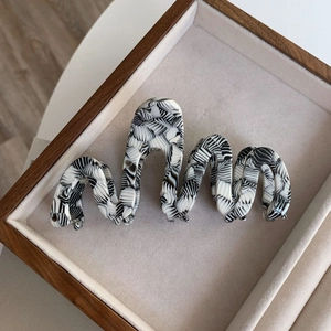 Detailed top view of a wave-shaped acetate hair claw with black and white marble patterns