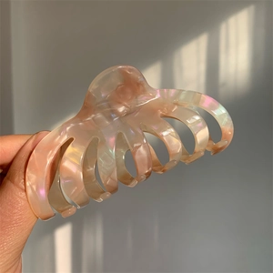 Close-up of a large pearlescent peach acetate hair claw with textured marble finish