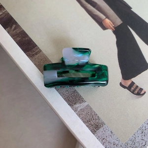 Detail of green and white marbled acetate hair claw clip on a stylish magazine surface