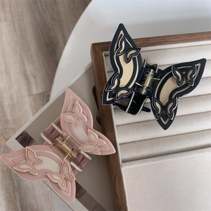 Detail of two butterfly-shaped hair claws with hollow design and smooth resin texture