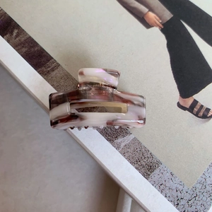 Close-up of pink and white marble acetate hair claw clip on a lifestyle magazine