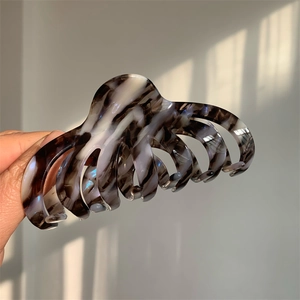Macro detail of large marble acetate hair claw clip showing glossy texture and strong teeth