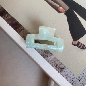 Close-up of mint green marble pattern acetate square hair claw clip on a magazine