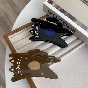 Detailed view of glossy black and brown acetate cat claw clips on a wooden jewelry tray