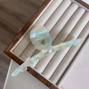 Detail of large acetate hair claw clip with light green and pearl white marble pattern