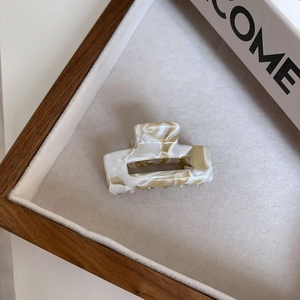 Detailed close-up of marble pattern acetate hair claw clip on soft velvet tray