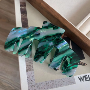 Vue détaillée d'une grande pince à cheveux marbrée verte sur une revue de mode