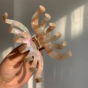 Detail showing iridescent marble texture and golden spring of a large hair claw clip