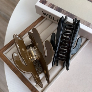 Detailed close-up of cactus-shaped shark hair clips in glossy black and dark brown colors