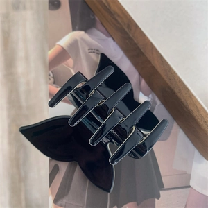 Close-up of gloss black butterfly hair claw with six-teeth design on magazine