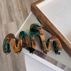 Detailed view of large green and amber acetate hair claw with wavy marble texture