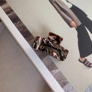Detail view of the elegant marble pattern square hair claw clip on a lifestyle magazine