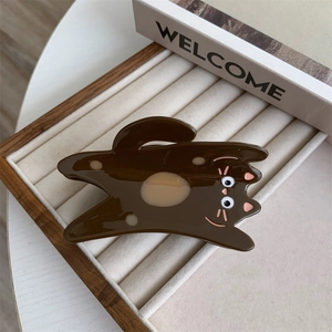 Detailed shot of dark brown acetate cat hair claw clip on soft beige jewelry display