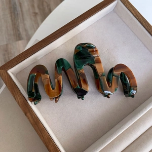 Macro detail of large acetate claw clip with wavy design and marbled green texture