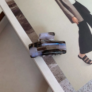 Detailed texture view of a rectangular purple marble acetate hair claw clip on a magazine