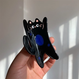 Close-up of a black cartoon cat hair claw clip made of glossy acetate material