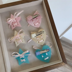 Détail de barrettes à cheveux en acétate avec nœuds en satin rose et formes d'étoile