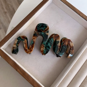 Macro shot of oversized marble acetate hair claw clip with vintage wavy design textures
