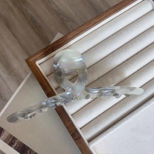 Detailed view of large grey marble acetate hair claw with heart cutout on wooden tray