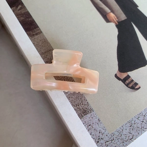 Detailed macro view of peach-orange marble acetate hair claw with hollow square design