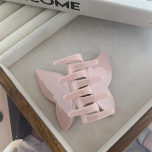 Detail view of pink butterfly hair claw clip with glossy finish on velvet tray