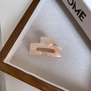 Detail shot of a small square acetate hair claw with pink marble pearlescent texture