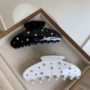 Détail de pinces à cheveux noires et blanches avec strass colorés dans un coffret