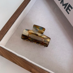 Detail view of square amber acetate hair claw clip with vintage tortoise texture on velvet
