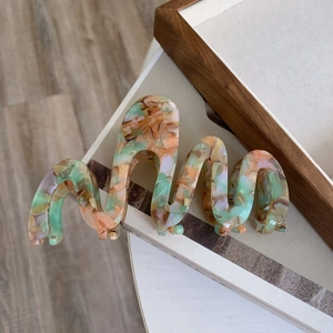 Detail of wavy acetate hair claw with multicolored marble pattern and smooth finish