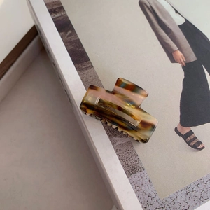 Macro shot of tortoiseshell acetate hair claw clip on an open magazine page