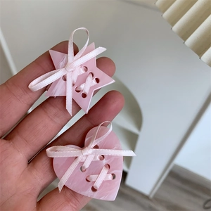 Vue détaillée de barrettes roses en acétate en forme d'étoile et de cœur avec rubans