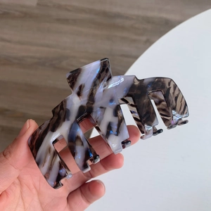 Détail macro d'une pince à cheveux en acétate montrant la texture marbrée et écaille