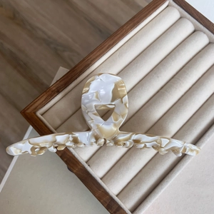 Macro view of a large acetate hair claw clip with cream marble pattern on velvet