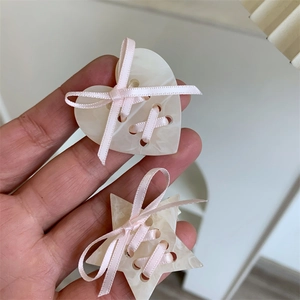 Vue détaillée des pinces à cheveux cœur et étoile avec rubans roses et texture marbre
