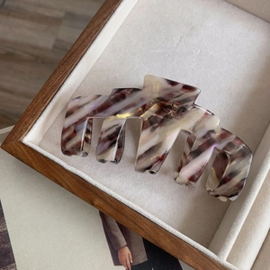 Détail d'une grande pince à cheveux en acétate avec texture marbrée en boîte bois