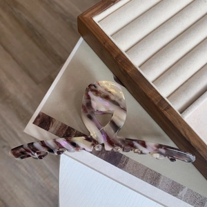 Detail view of large acetate claw clip with purple and white marble pattern on wood