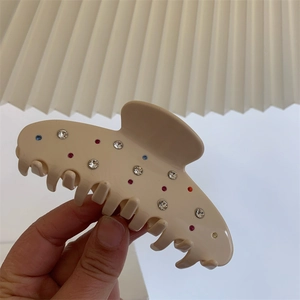 Détail d'une pince à cheveux crème ornée de strass colorés étincelants pour femmes