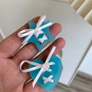Détail de barrettes bleues en acrylique en forme d'étoile et de cœur avec ruban rose