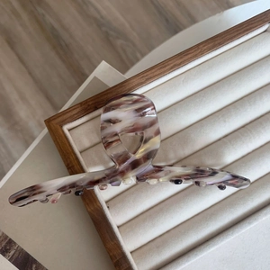 Detail of large acetate hair claw clip featuring purple marble texture on jewelry tray