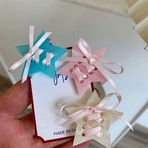 Trois pinces à cheveux étoiles en acétate avec rubans en bleu, rose et beige pastel