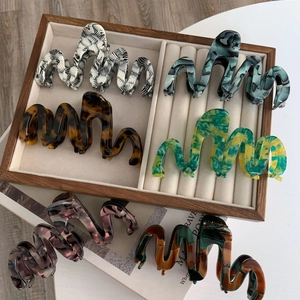 Oversized wavy acetate hair claws in various marble and tortoiseshell patterns