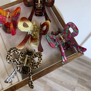 Detail view of assorted acetate bow hair claws in leopard, marble, and colorful patterns