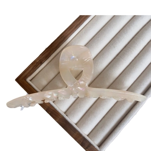 Elegant large pearlescent white acetate shark hair claw clip on wooden display tray