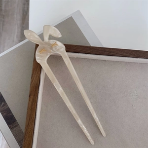 Dettaglio della forcina per capelli a coniglio in acetato con finitura color crema e oro